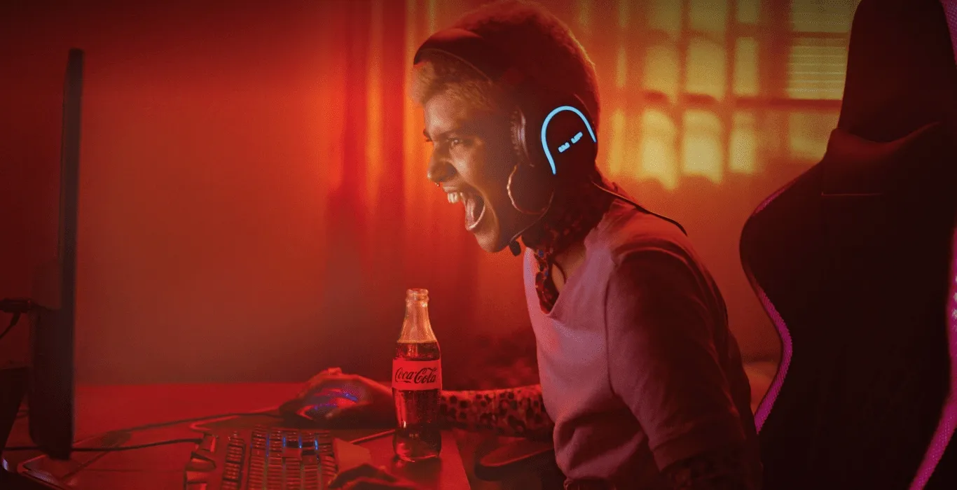 Gamer playing on a desktop computer with a Coca-Cola bottle